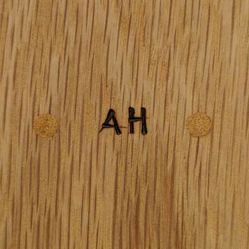 A piece of wood with the initials 'AH' burned in